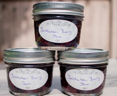 four jars filled with jam sitting on top of a wooden table