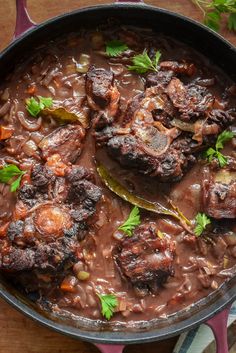 a pot filled with meat and vegetables on top of a wooden table