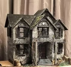 a doll house made out of wood and stone with vines growing on the front porch