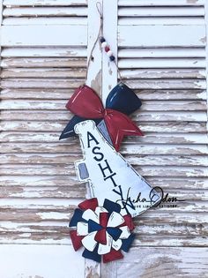 a wooden sign with a red, white and blue bow hanging from it's side