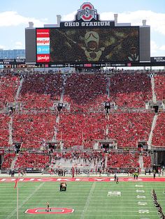 a football stadium filled with lots of red and white fans sitting on the sidelines