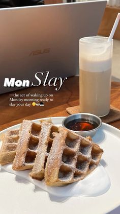 two waffles on a plate next to a glass of milk and a laptop