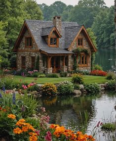 a house sitting next to a lake surrounded by lush green trees and flowers in front of it