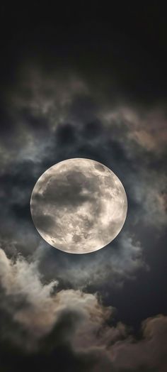 the full moon is seen through dark clouds