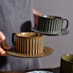 a person is holding two plates with cups on them and one has a cup in the middle