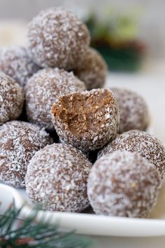 a white plate filled with powdered sugar covered donuts next to a christmas tree