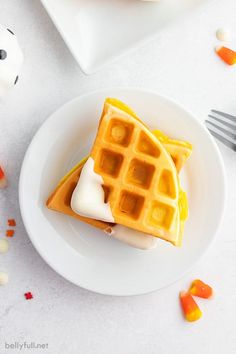 two waffles are sitting on a plate with white frosting and candy candies