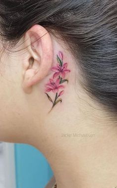 a woman with a pink flower tattoo on her left side behind the ear is looking down