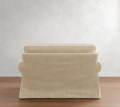 a beige couch sitting on top of a hard wood floor next to a white wall