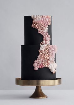 a black cake with pink and white decorations on it