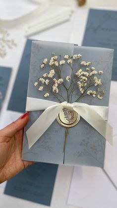 a person holding up a card with flowers on it and a ribbon around the front