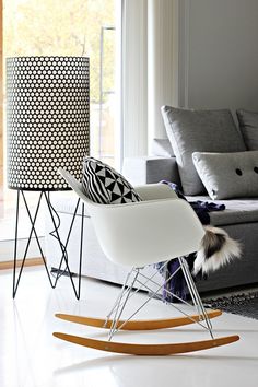 a living room filled with furniture and a white rocking chair in front of a window