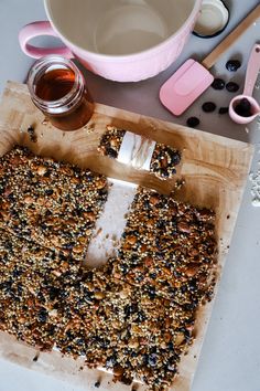 a wooden cutting board topped with granola bars next to a cup of coffee and utensils