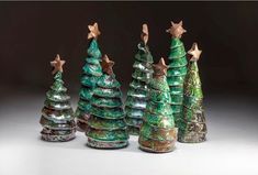 three ceramic christmas trees with gold stars on top and one decorated in green, brown and white