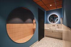 a bathroom with blue walls and white tile on the floor is seen through a circular mirror