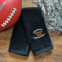 two black towels sitting on top of a wooden floor next to a football and silver tinsel