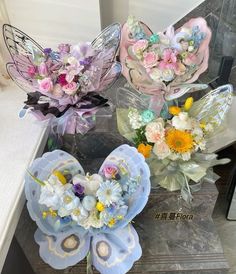 three vases filled with flowers sitting on top of a marble table next to each other