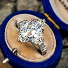 a diamond ring sitting in a velvet box on top of some rocks and stones,