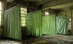 an abandoned building with green curtains hanging from the ceiling