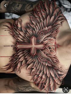 a cross tattoo on the back of a man's upper arm and shoulder with wings