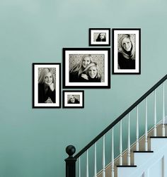 black and white photo frames hanging on the wall next to a stair case in a home