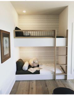 there is a bunk bed with two stuffed animals on it in the room that has white walls and wood flooring