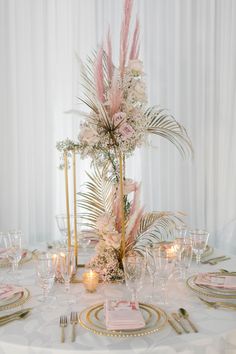 the table is set with pink and gold place settings, silverware, and flowers