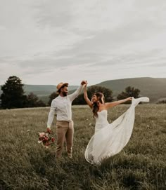 a bride and groom holding hands in a field