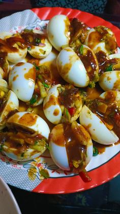 an egg dish on a red and white plate with sauce over the top, sitting on a table