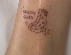 a woman's foot with a tattoo that reads dancing queen and a boot on it