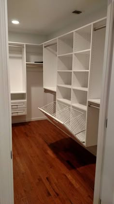 an empty walk in closet with white shelving and wood flooring on the wooden floor