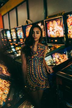 a woman is standing in front of some pinball machines and looking at the camera