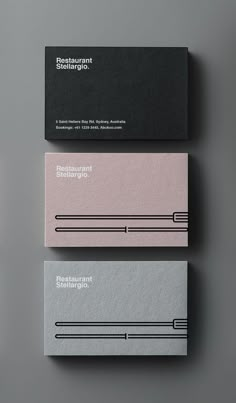 three business cards with black and white lines on the front, one in grey and one in pink