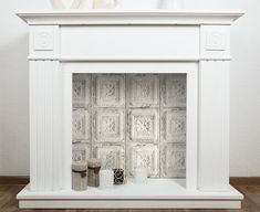 a white fireplace with decorative tiles on the mantle