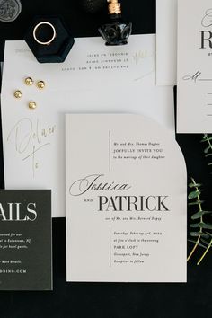 the wedding stationery is laid out on top of the black and white table cloth