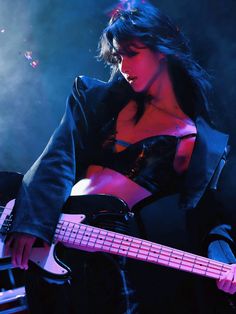 a woman holding a bass guitar on stage