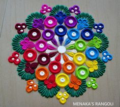 a circular design made out of different colored buttons and yarns on a wooden surface