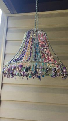 a chandelier hanging from the side of a house with beads all over it