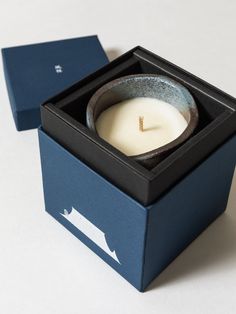 a candle in a blue box on a white table