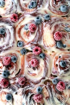 a close up of a cake with blueberries and raspberries on it's icing