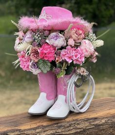 a pink boot with flowers in it is sitting on a log