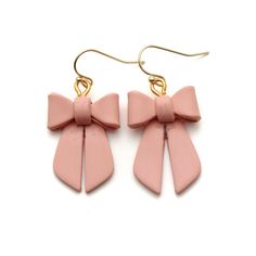 the pink bow earrings are hanging from gold hooks