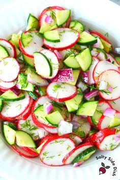 a white bowl filled with cucumber and radishes on top of a table