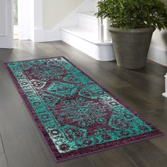 a green and purple rug on the floor next to a stair case with potted plant