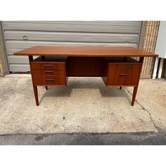 a wooden desk sitting on top of a cement floor next to a garage door and wall