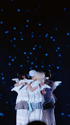 the group of girls are hugging each other on stage with their arms around one another