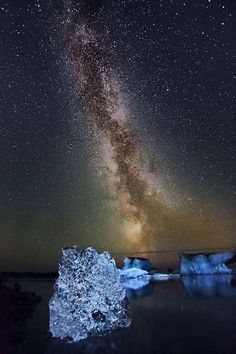 the night sky is filled with stars above icebergs and an ice floet