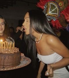 two women blowing out candles on a cake