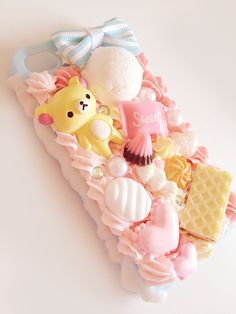 a cell phone case that has various candies and other items on it, all in pastel colors