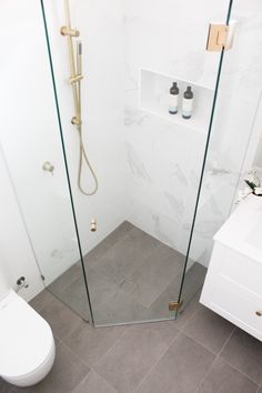 a white toilet sitting next to a shower in a bathroom on top of a tiled floor